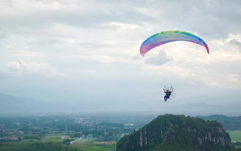 Atlet paralayang sedang terbang menggunakan paramotor di langit Bukik Soriak.